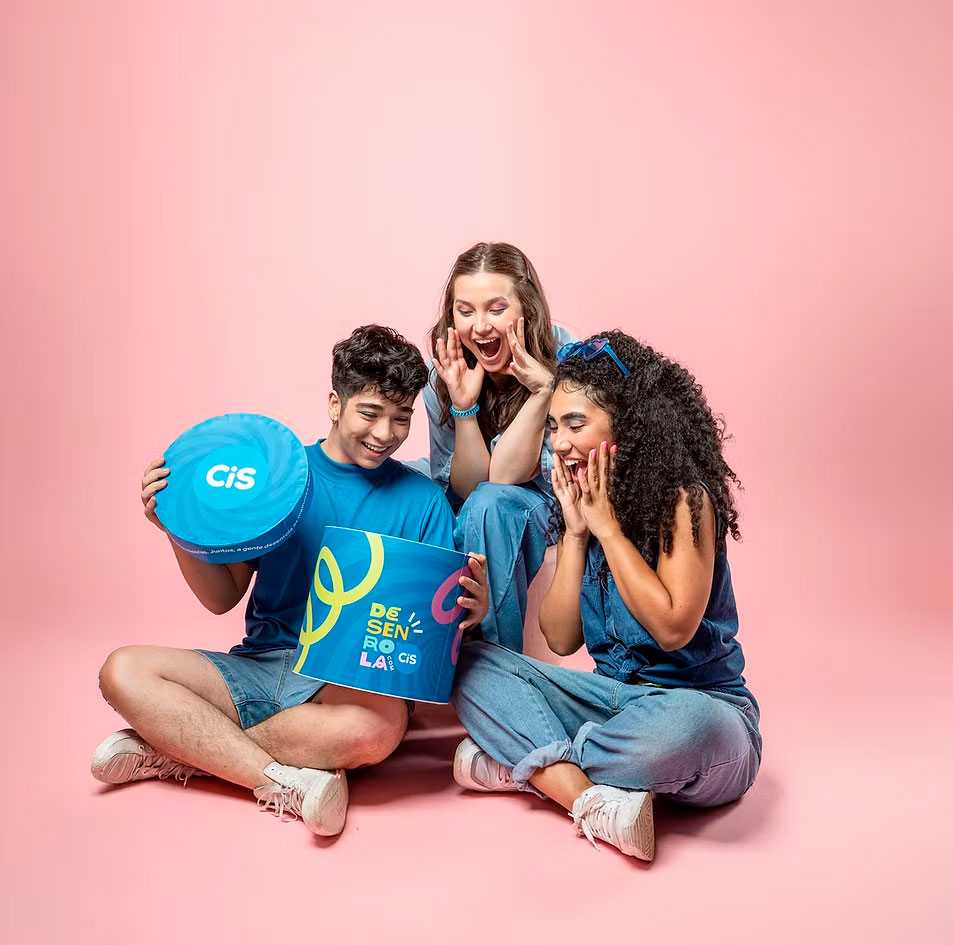 Trio com press kit da CiS em estúdio rosa